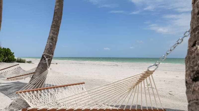 Hammocks on a quiet Sanibel Island beach, one of the best beaches near Cape Coral for slow days.