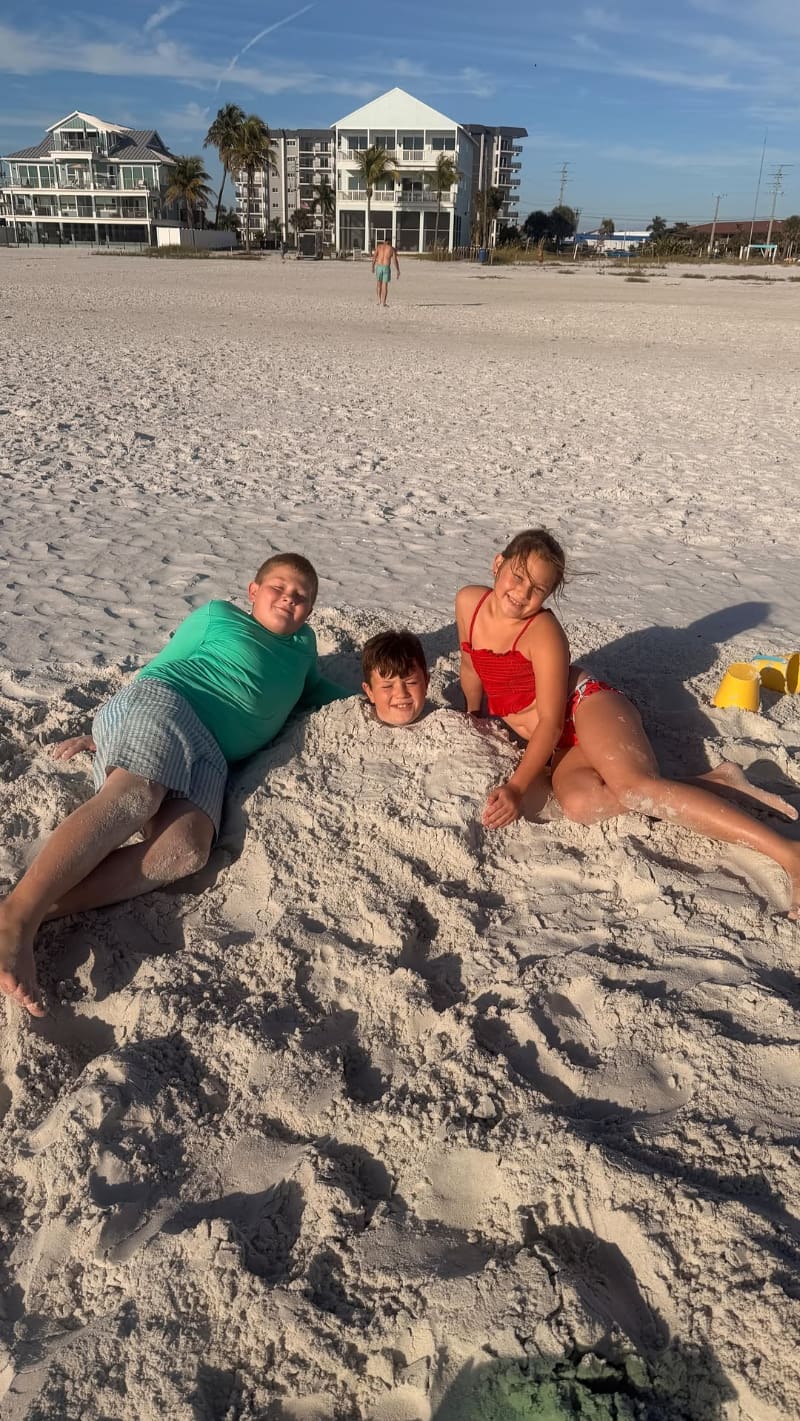 Children playing together in soft sand, smiling and enjoying a relaxed beach afternoon.