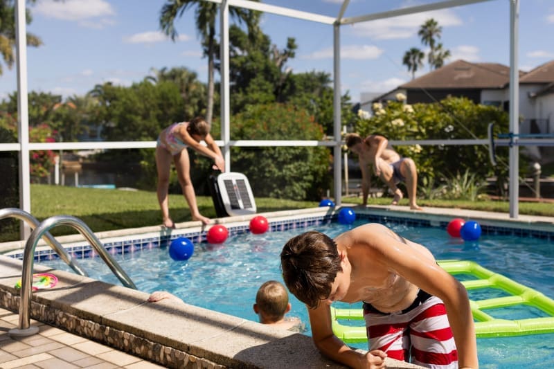 Kids playing in a backyard pool on a sunny day in the Cape Coral climate