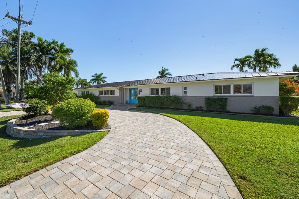 Bright waterfront home with palm trees and curved driveway, perfect setting for a relaxing girls’ getaway in Cape Coral