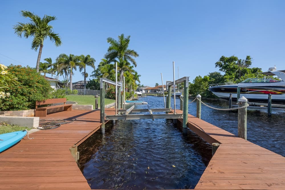 Cape Coral Vacation Rentals with private dock, canal view, palm trees, and boat lift under clear sky