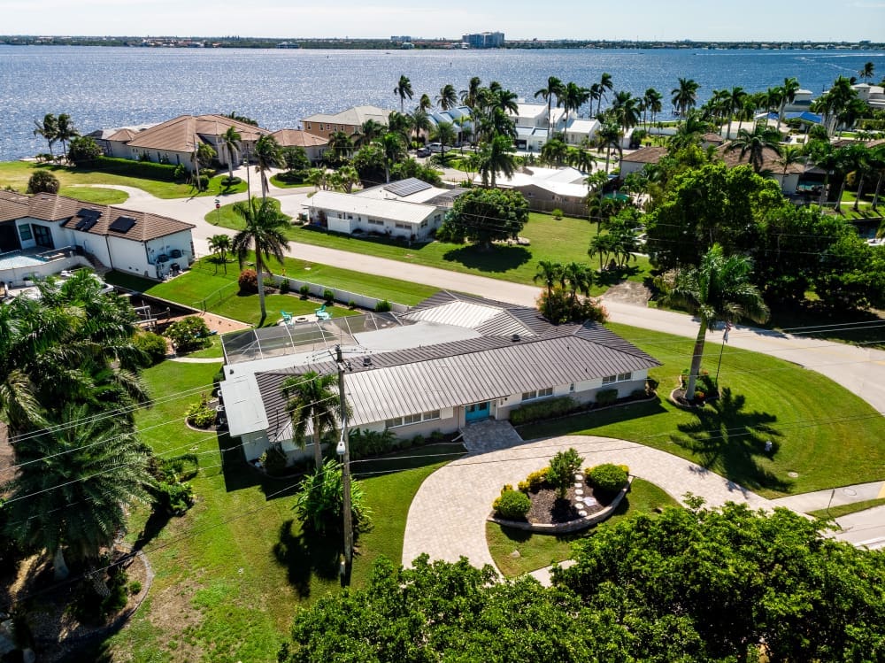 Cape Coral Vacation Rentals aerial view with waterfront home, palm trees, canal access, and private pool area