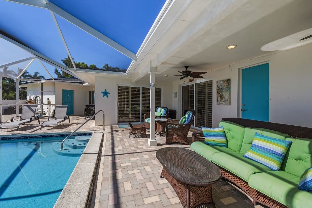 Screened patio at Florida house rentals with a pool, cozy seating, sunny lanai, and inviting outdoor living space