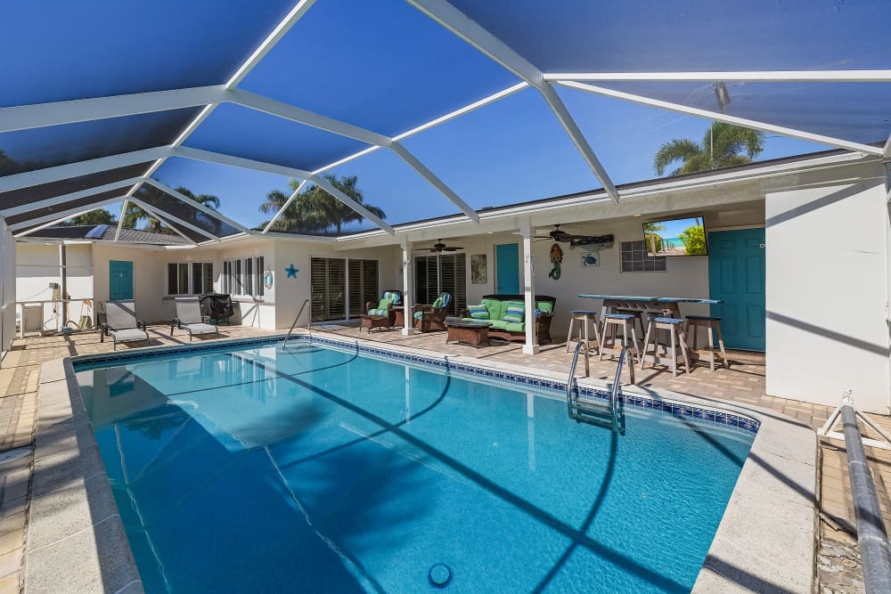 Screened lanai pool at Florida house rentals with a pool, bright patio seating and outdoor bar area