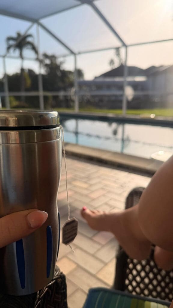 Morning tea by the pool, relaxed legs up, soft sunlight, and quiet outdoor patio view