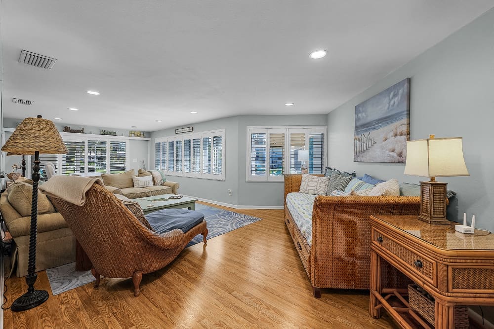 A bright coastal-inspired living room features comfortable seating, natural textures, and large windows that fill the space with light. After beach days and outdoor adventures, this welcoming gathering space encourages guests to relax, reconnect, and unwind together.