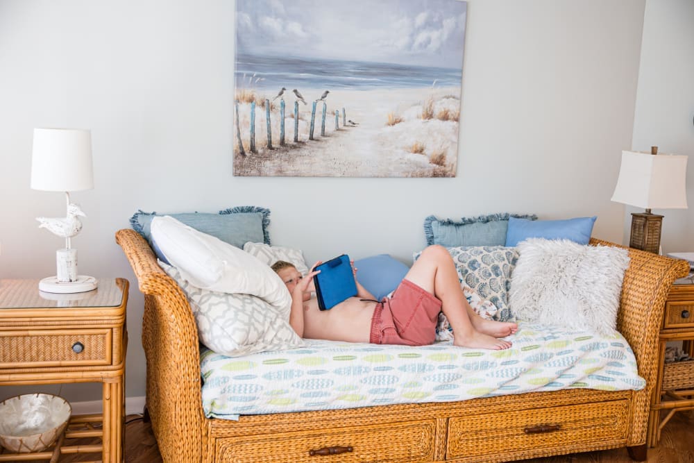 A child relaxes on a wicker daybed with a tablet inside South Del Prado Point. Comfortable spaces for downtime give families a chance to recharge between beach trips, pool time, and local adventures around Cape Coral- all part of this Florida vacation guide. 